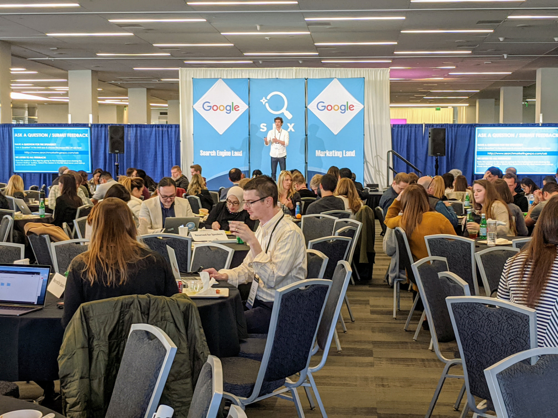 A speaker on stage presenting to a packed audience at SMX Search Marketing Expo in San Jose, with Search Engine Land and Google signage