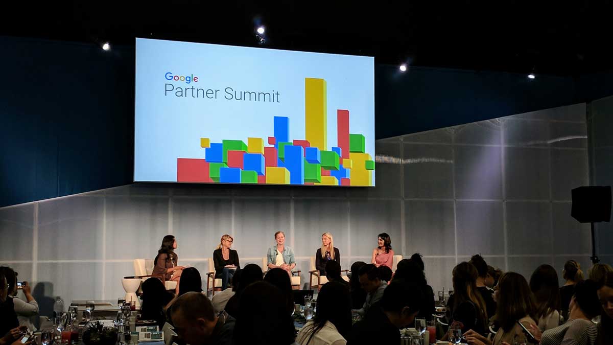 Panel discussion on stage at the Google Partner Summit in New York City, with the Google Partner Summit logo displayed on a large screen